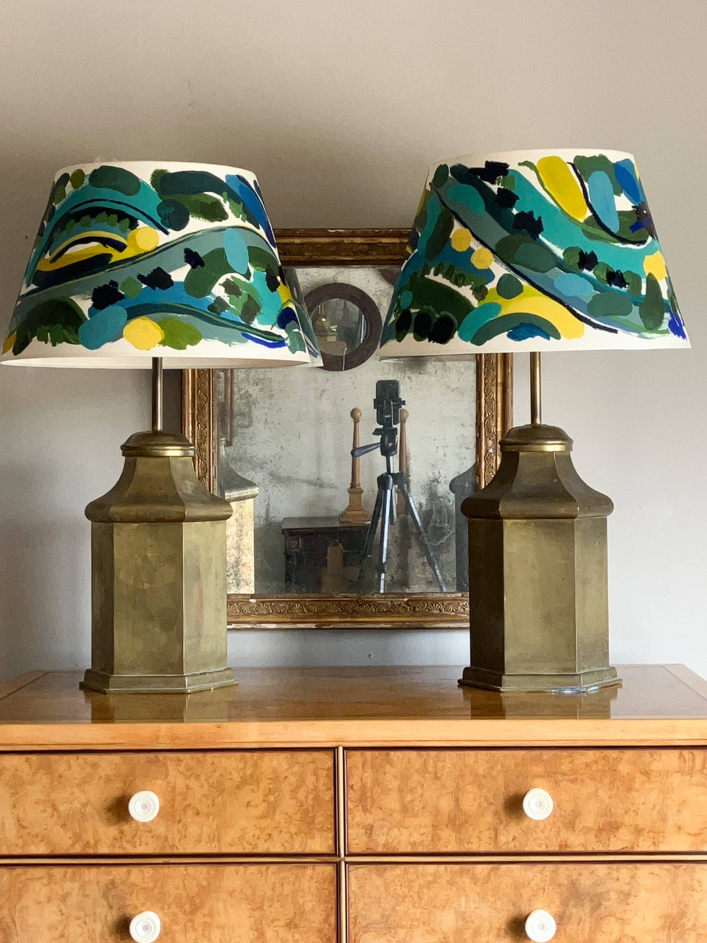 Two lamps with colorful lampshades on a wooden dresser.